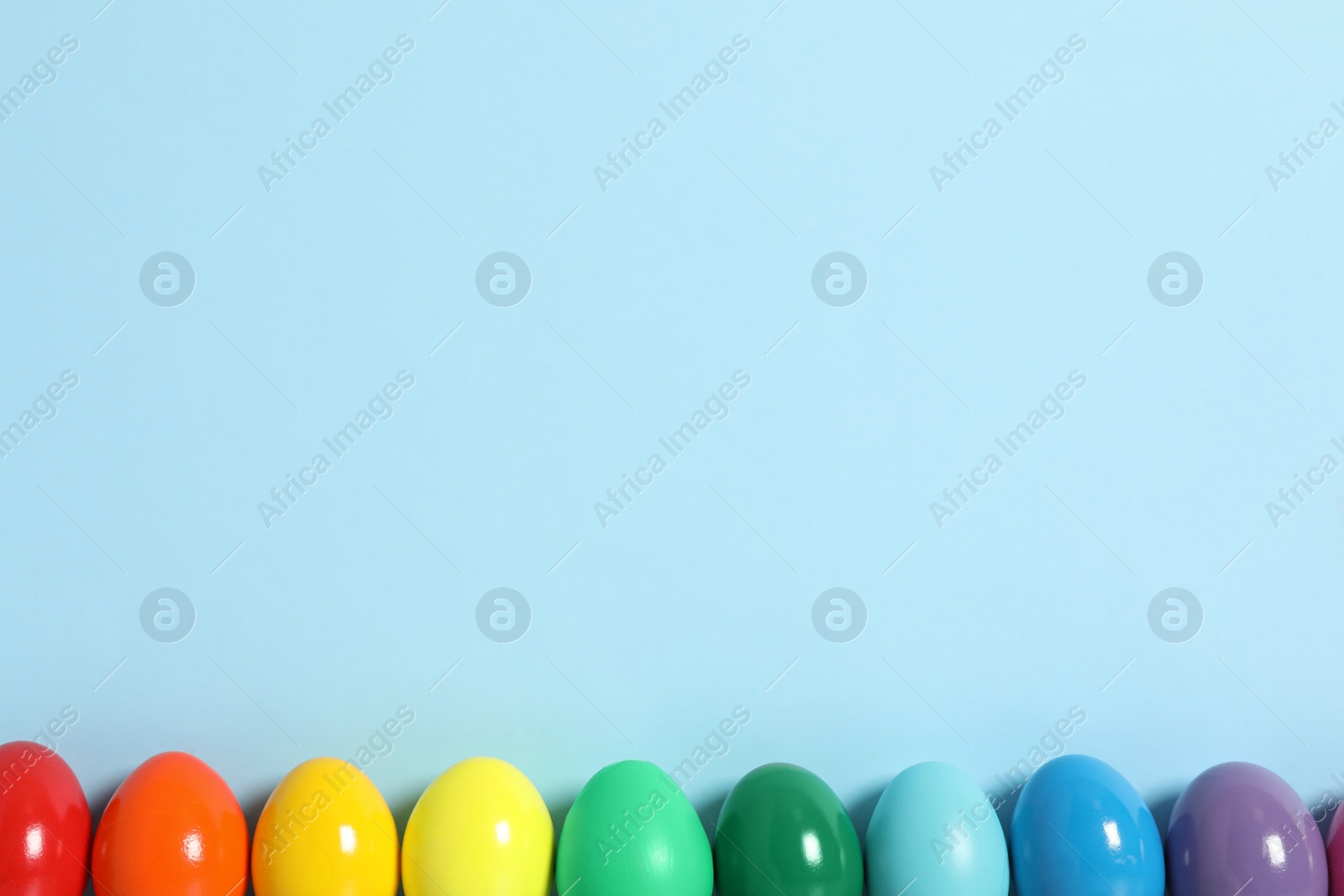 Photo of Easter eggs on light blue background, flat lay. Space for text