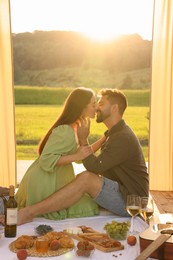 Photo of Romantic date. Beautiful couple kissing during picnic on sunny day