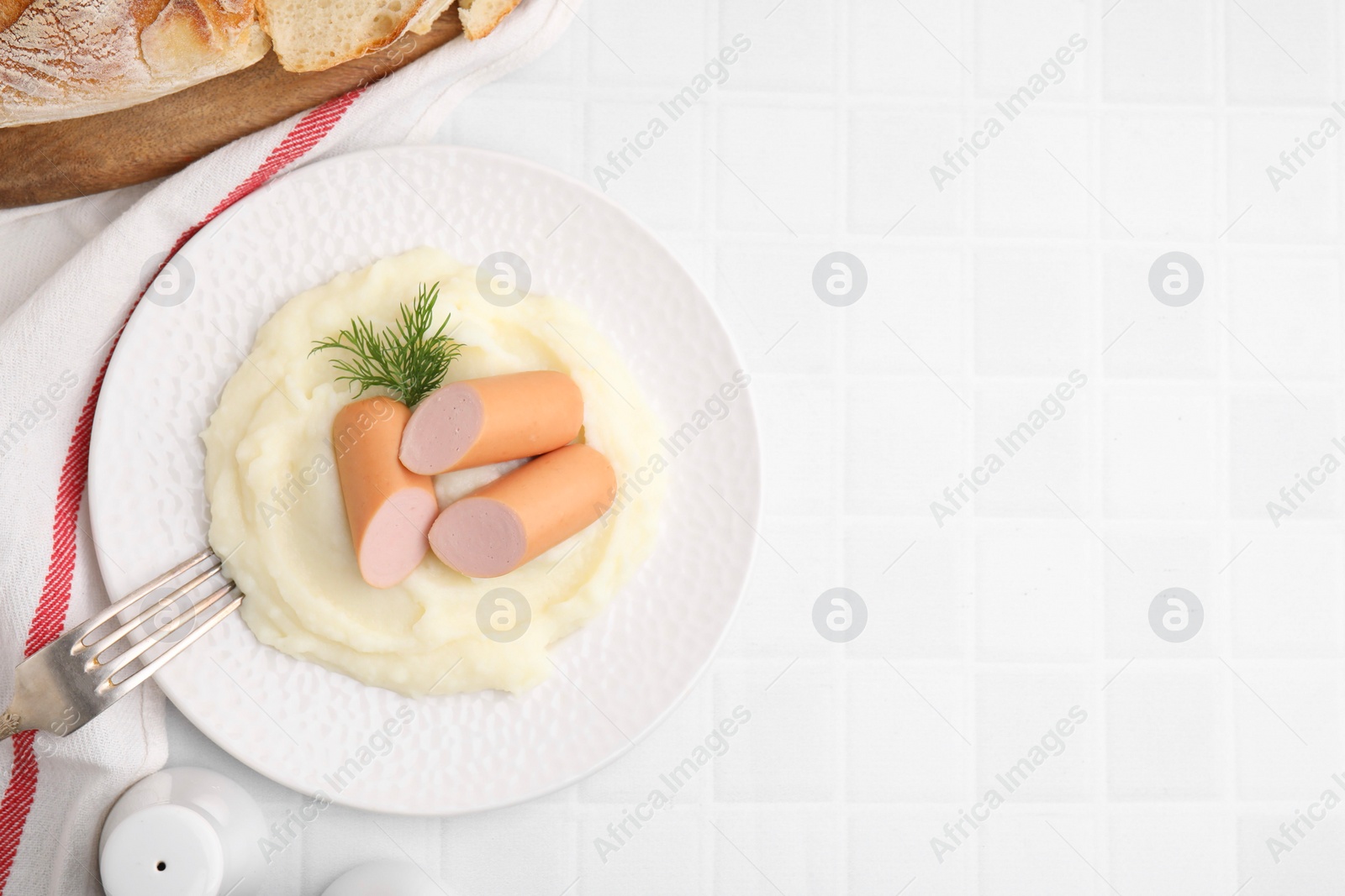 Photo of Delicious boiled sausages and mashed potato on white tiled table, top view. Space for text