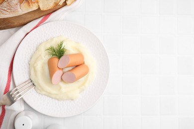 Delicious boiled sausages and mashed potato on white tiled table, top view. Space for text