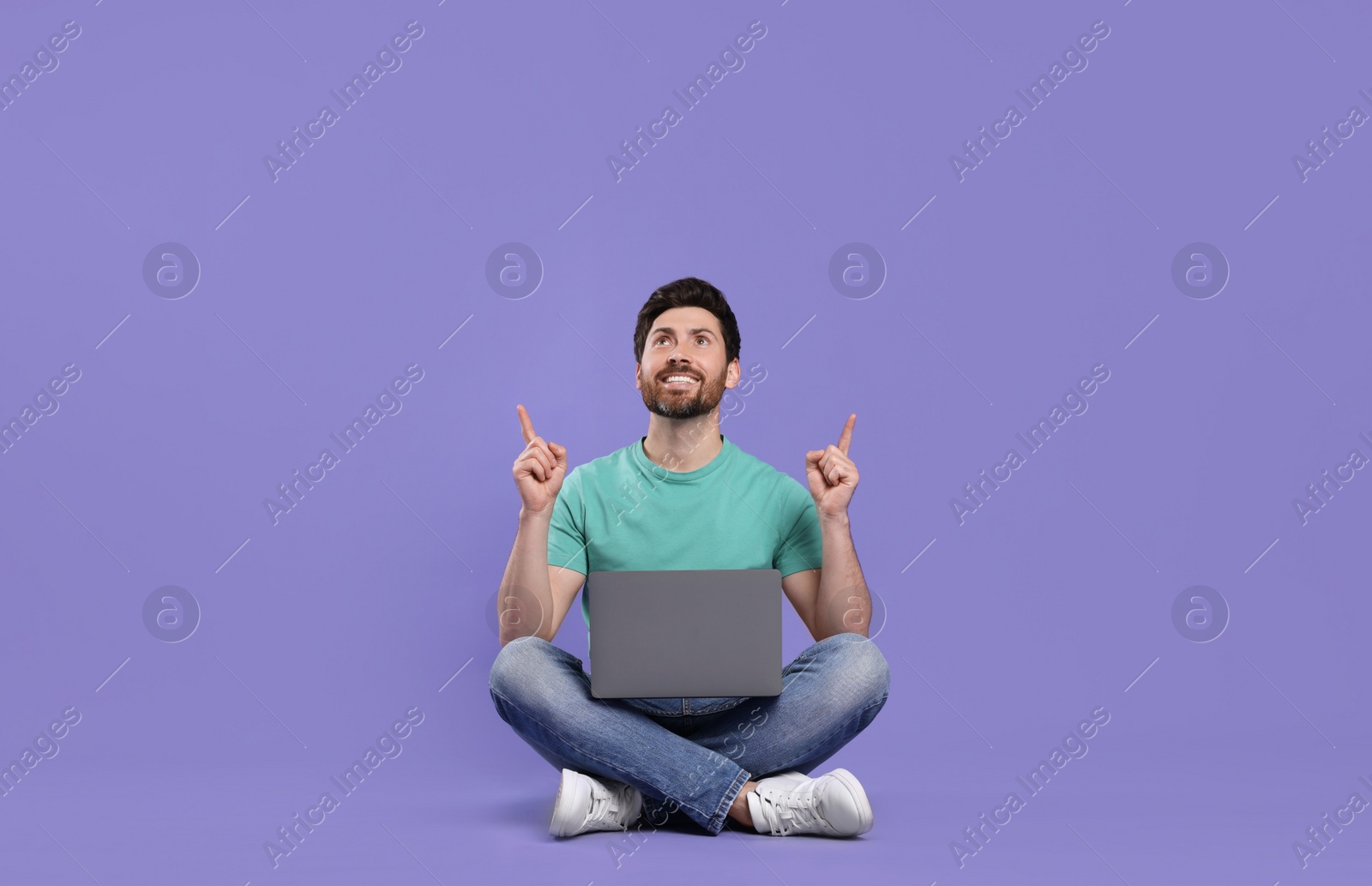 Photo of Happy man with laptop on purple background