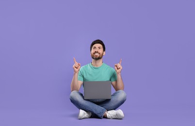 Happy man with laptop on purple background