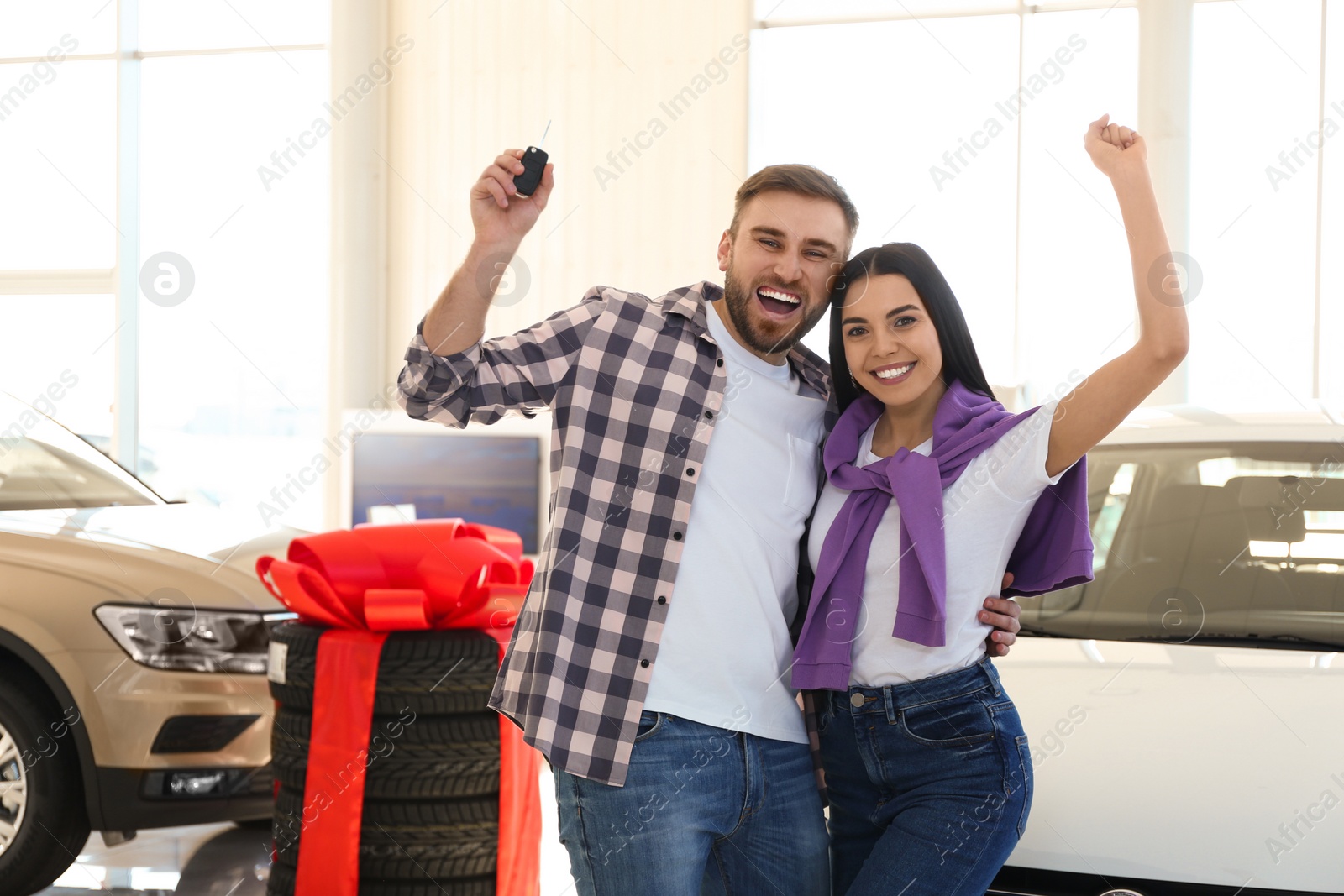 Photo of Happy couple with car key in modern auto dealership