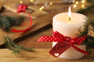 Photo of Burning candle with pinecone scent on wooden table, closeup. Space for text