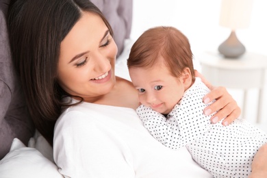 Happy woman with her cute baby on bed