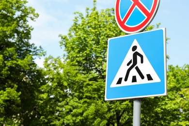 Photo of Post with Pedestrian Crossing and No Stopping road signs on sunny day