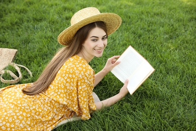 Photo of Young woman reading book on green grass