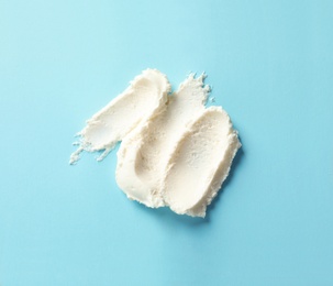 Photo of Smear of tasty cream cheese on color background, top view