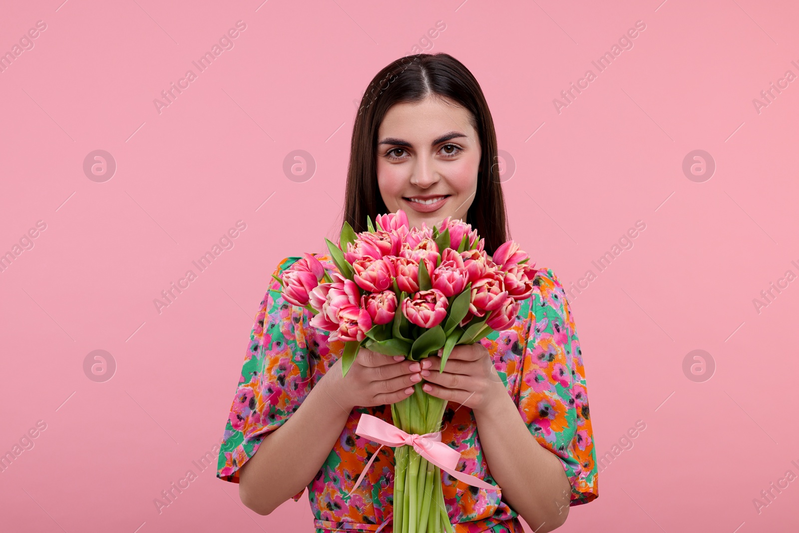 Photo of Happy young woman with beautiful bouquet on dusty pink background