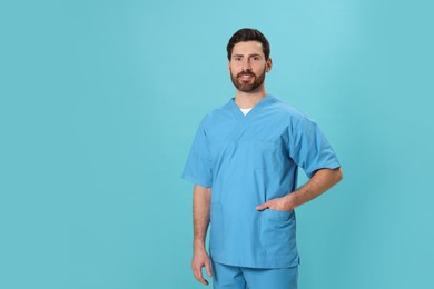 Photo of Happy nurse in medical uniform on light blue background, space for text