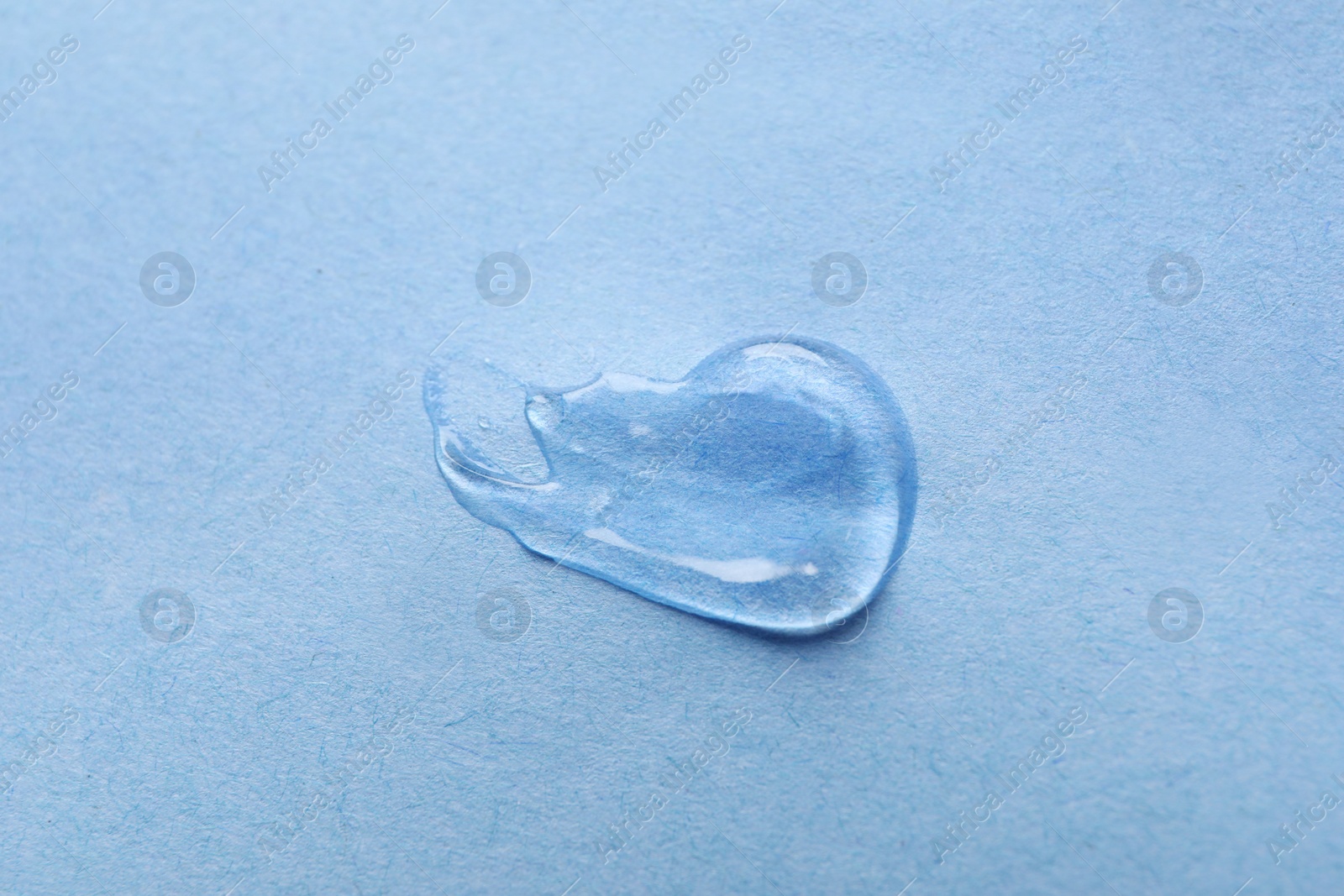 Photo of Sample of transparent gel on light blue background, closeup