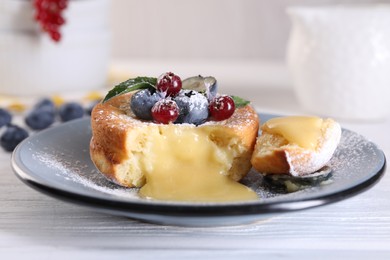 Photo of Tasty vanilla fondant with white chocolate and berries on light wooden table, closeup