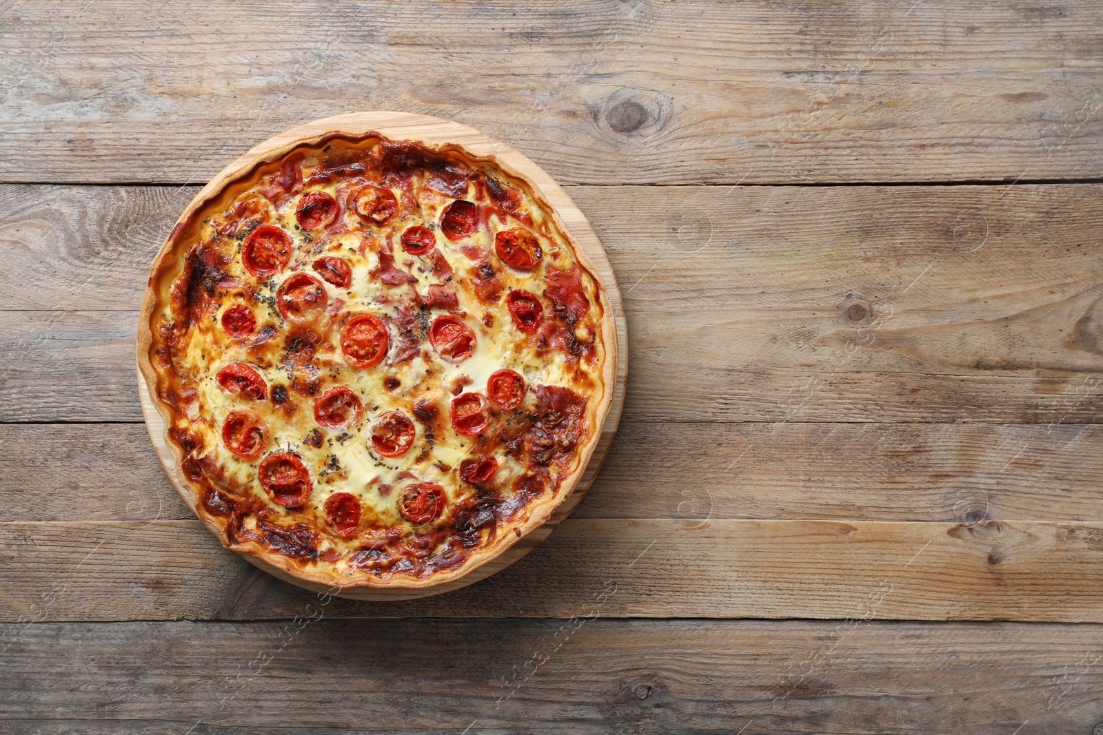 Photo of Delicious homemade quiche with prosciutto and tomatoes on wooden table, top view. Space for text