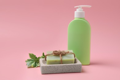 Photo of Soap bar and bottle dispenser on pink background
