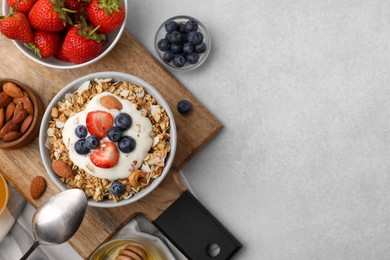 Tasty granola, yogurt and fresh berries served on light table, flat lay with space for text. Healthy breakfast