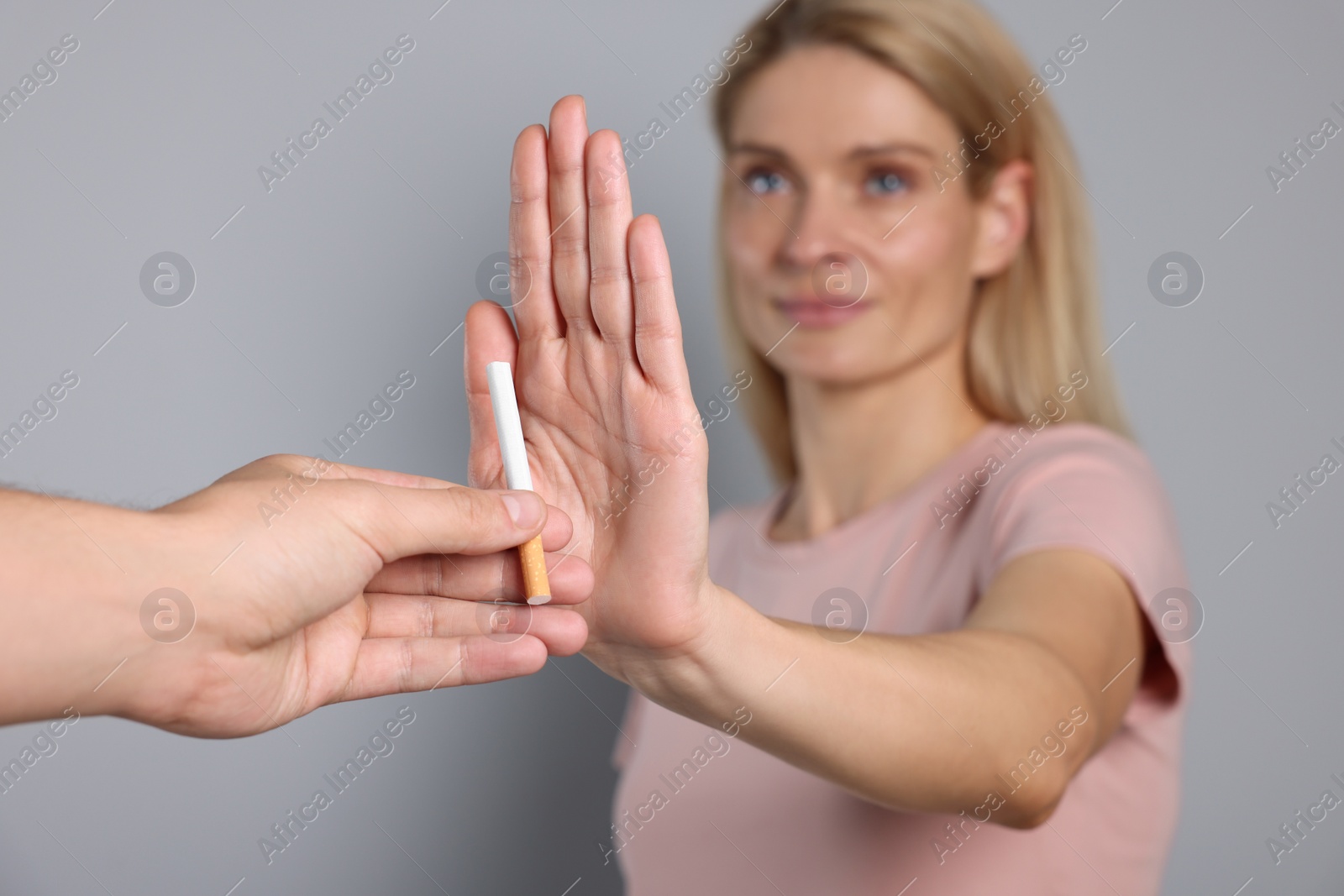 Photo of Woman refusing cigarette on light grey background, selective focus. Quitting smoking concept