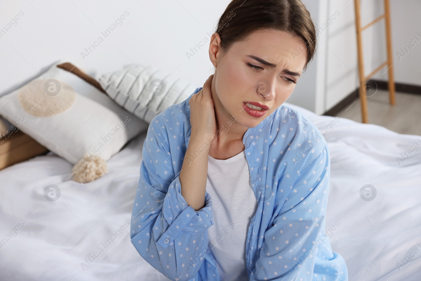 Photo of Woman suffering from neck pain in bedroom