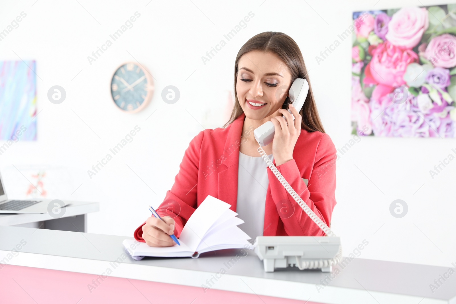 Photo of Beauty salon receptionist talking on phone at desk