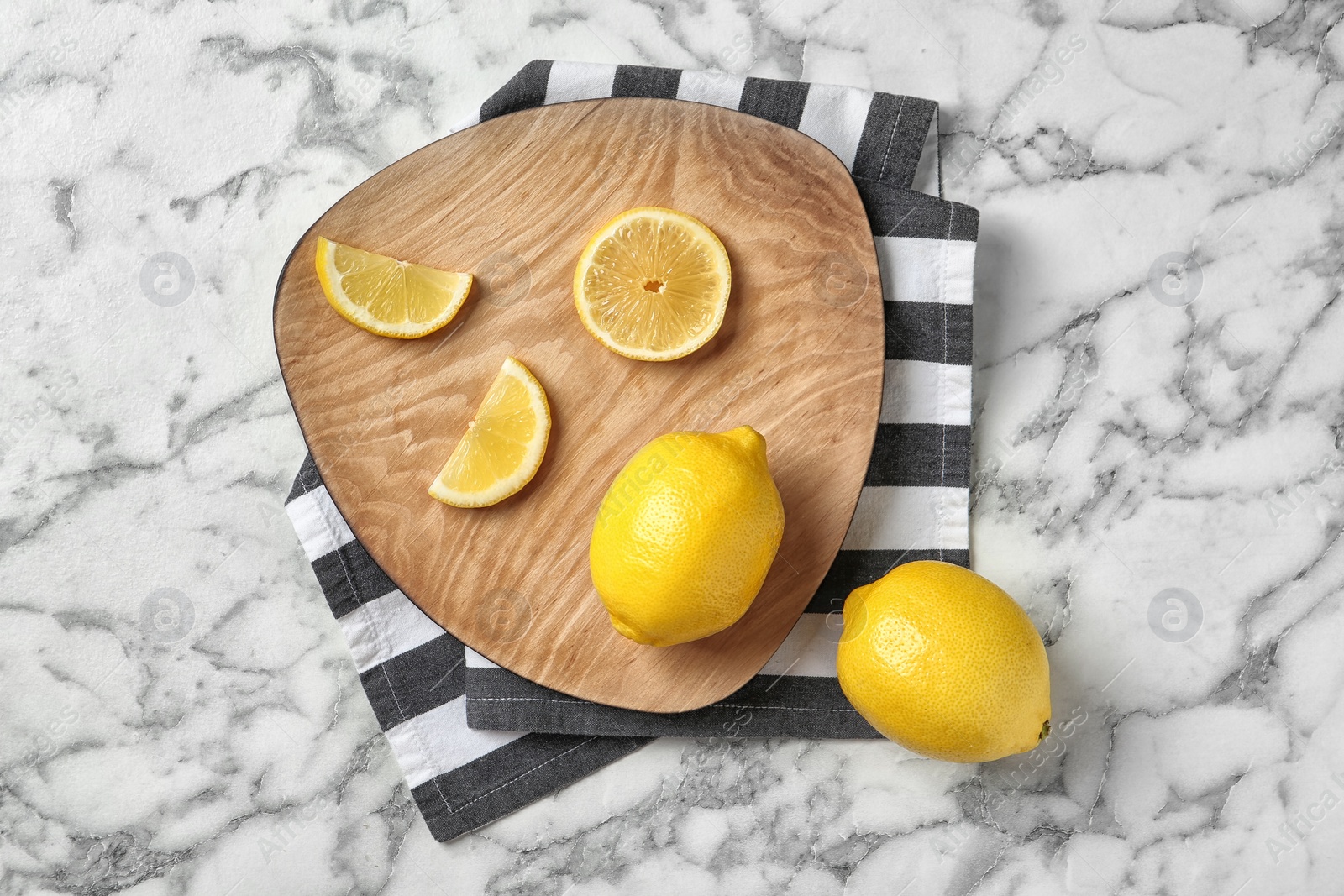 Photo of Wooden board with lemons on marble background, top view