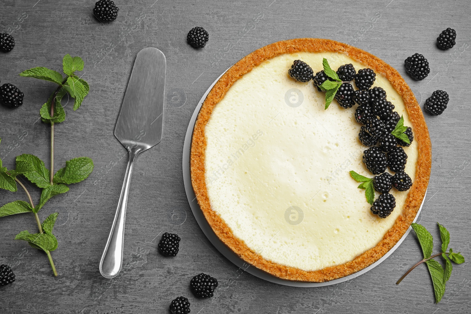 Photo of Delicious cheesecake decorated with blackberries on grey table, flat lay