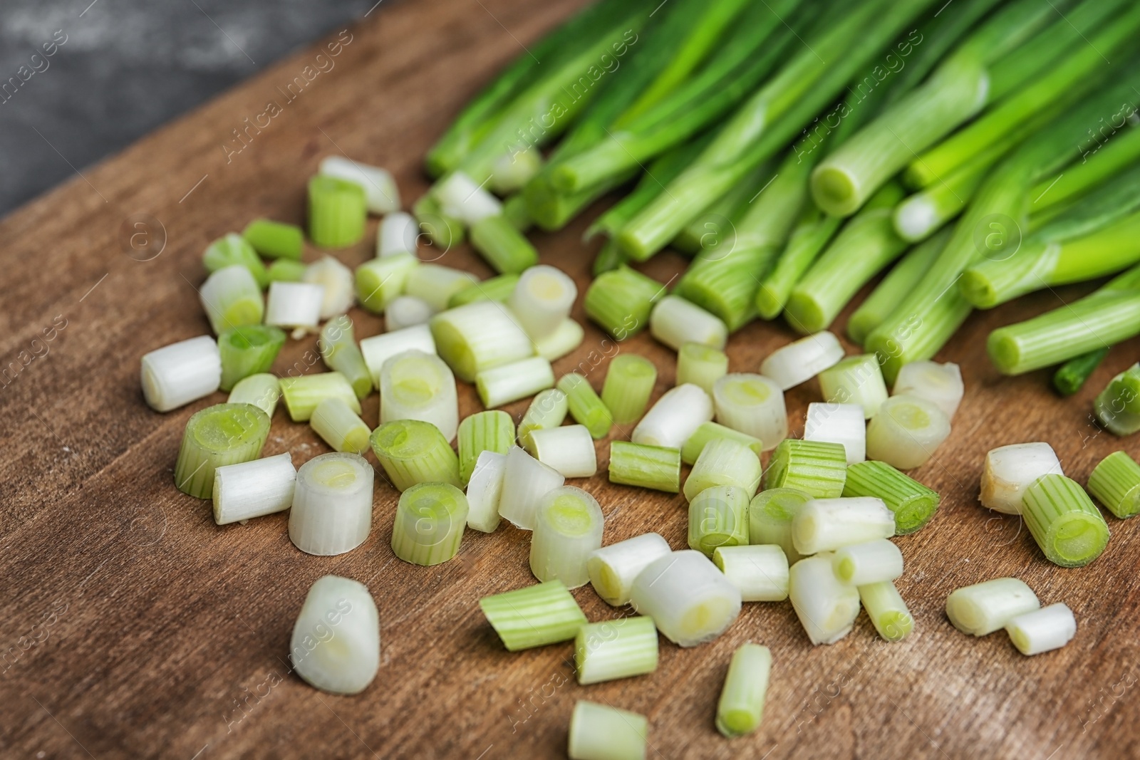 Photo of Chopped green onion on wooden board, closeup