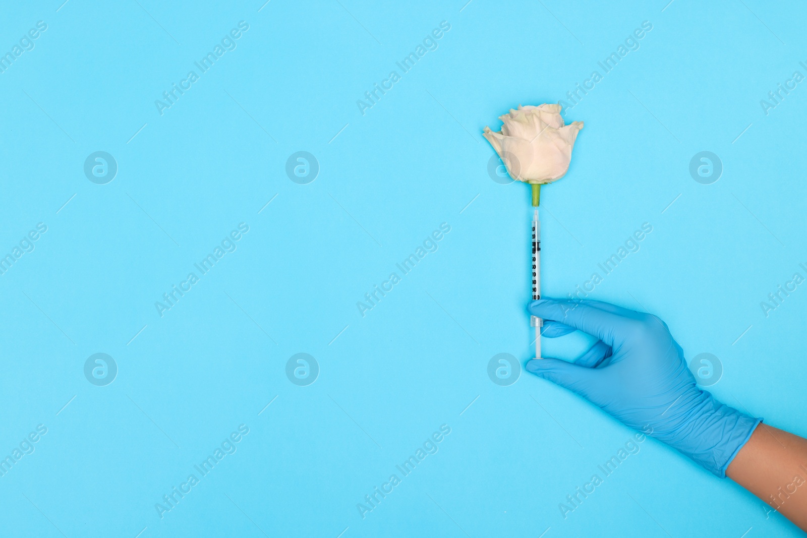 Photo of Doctor making injection to rose on light blue background, top view. Space for text