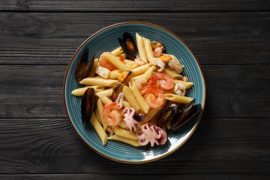 Photo of Delicious pasta with seafood served on black wooden table, top view