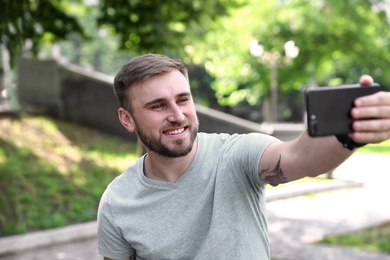 Photo of Happy young man taking selfie in park