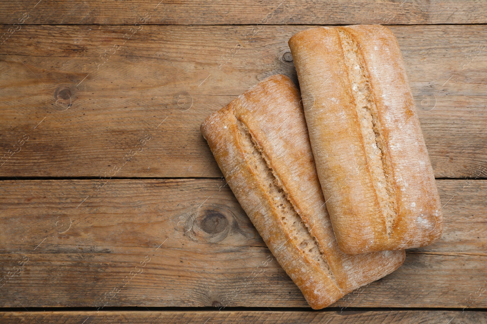 Photo of Delicious ciabattas on wooden table, flat lay. Space for text