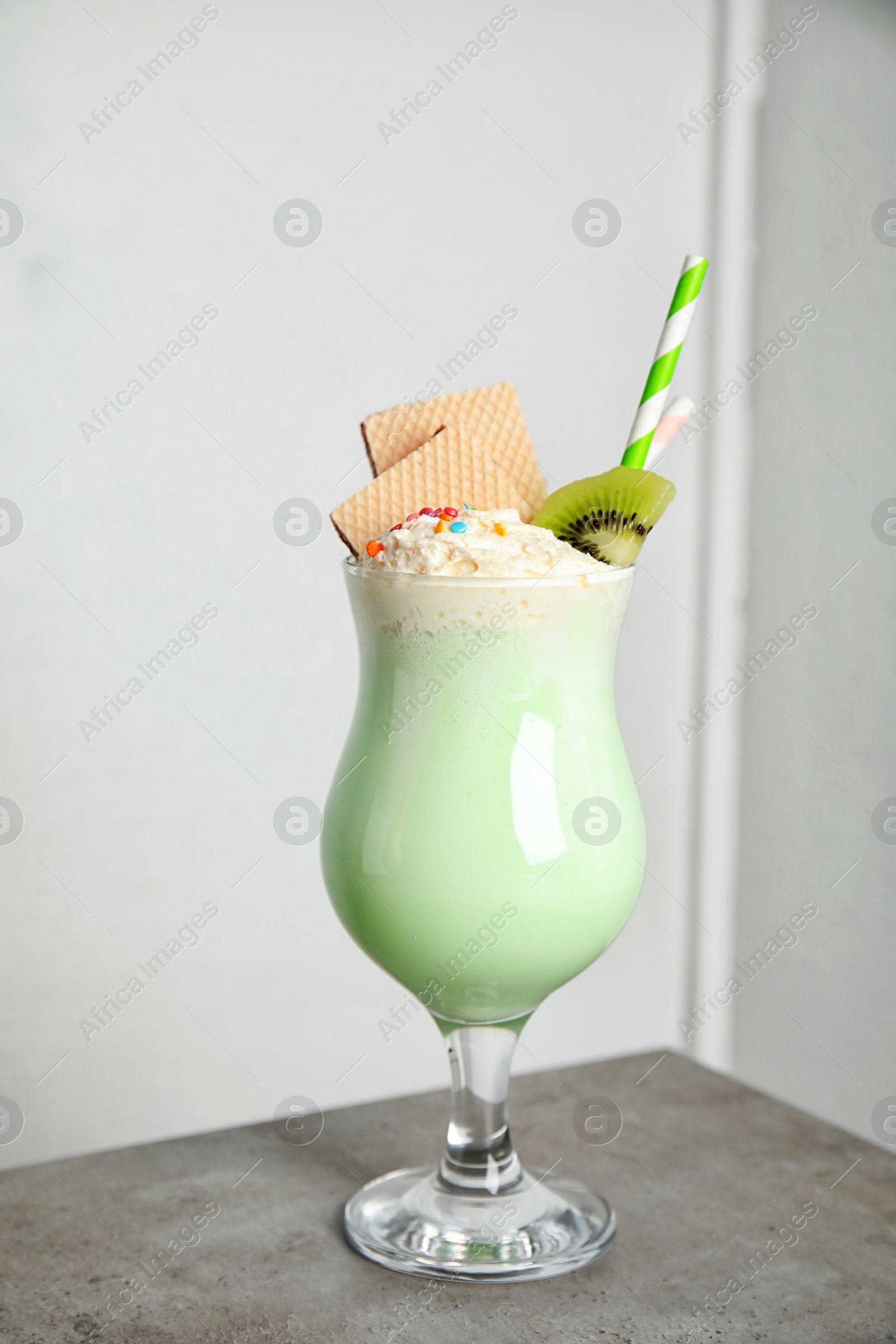 Photo of Glass with delicious milk shake on table against light background