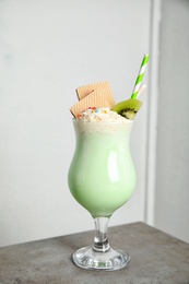 Photo of Glass with delicious milk shake on table against light background