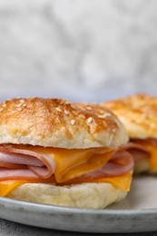 Delicious bagels with ham and cheese on table, closeup