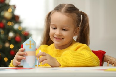 Photo of Cute little girl with paper Saint Nicholas toy at home