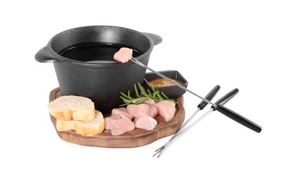 Photo of Fondue pot with oil, forks, raw meat pieces and other products isolated on white