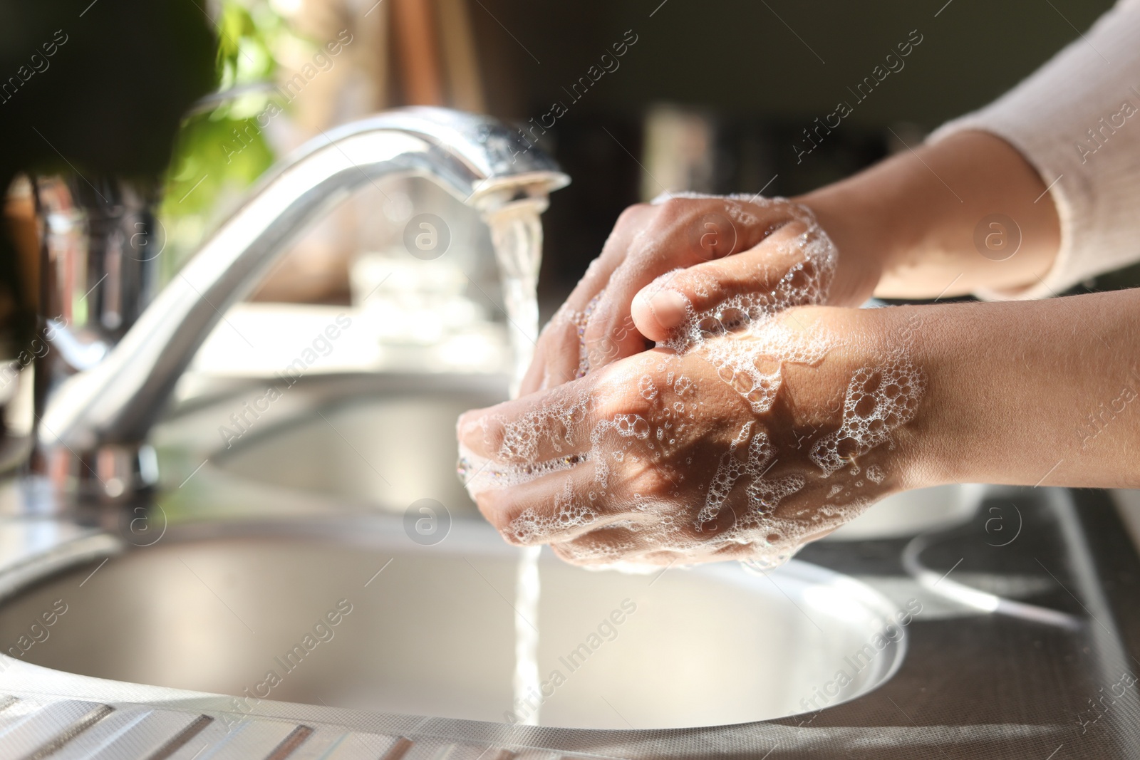 Photo of Woman washing hands in kitchen, closeup view