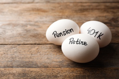 Photo of Eggs with words PENSION, RETIRE and 401k on wooden background. Space for text