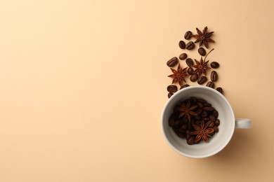 Photo of Cup with coffee beans and anise stars on beige background, flat lay. Space for text