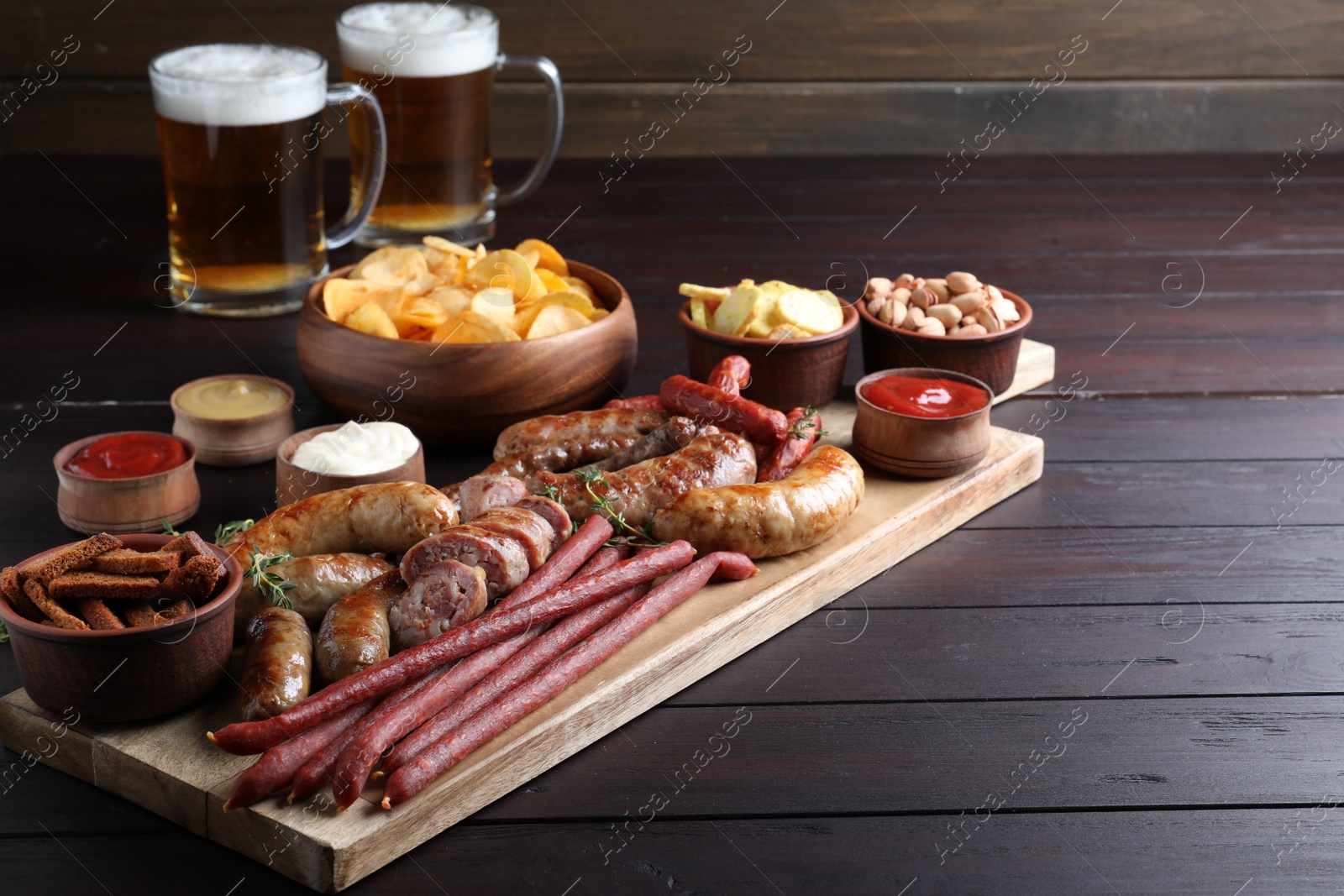 Photo of Set of different tasty snacks and beer on wooden table, space for text