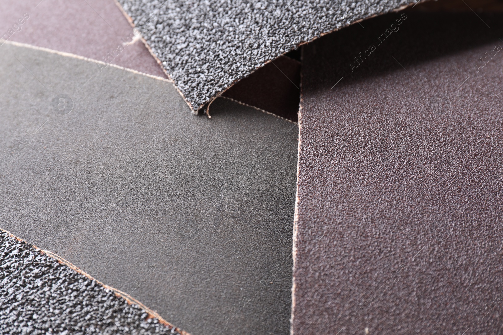 Photo of Many sheets of sandpaper as background, closeup