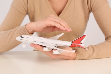 Photo of Woman covering toy plane at table, closeup. Travel insurance concept