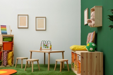 Stylish playroom interior with table and stools