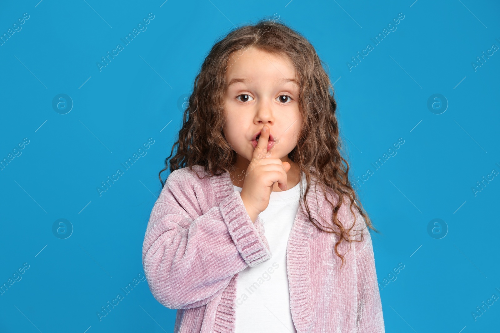 Photo of Portrait of cute little girl on light blue background