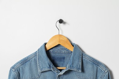 Hanger with denim shirt on white wall