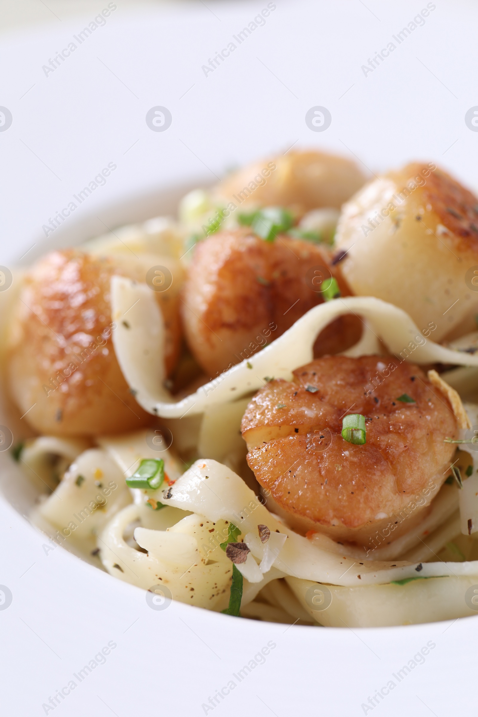 Photo of Delicious scallop pasta with spices in bowl, closeup