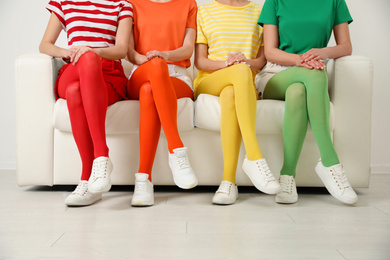 Photo of Women wearing bright tights sitting on sofa indoors, closeup