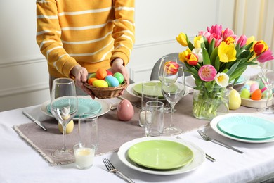 Woman setting table for festive Easter dinner at home, closeup