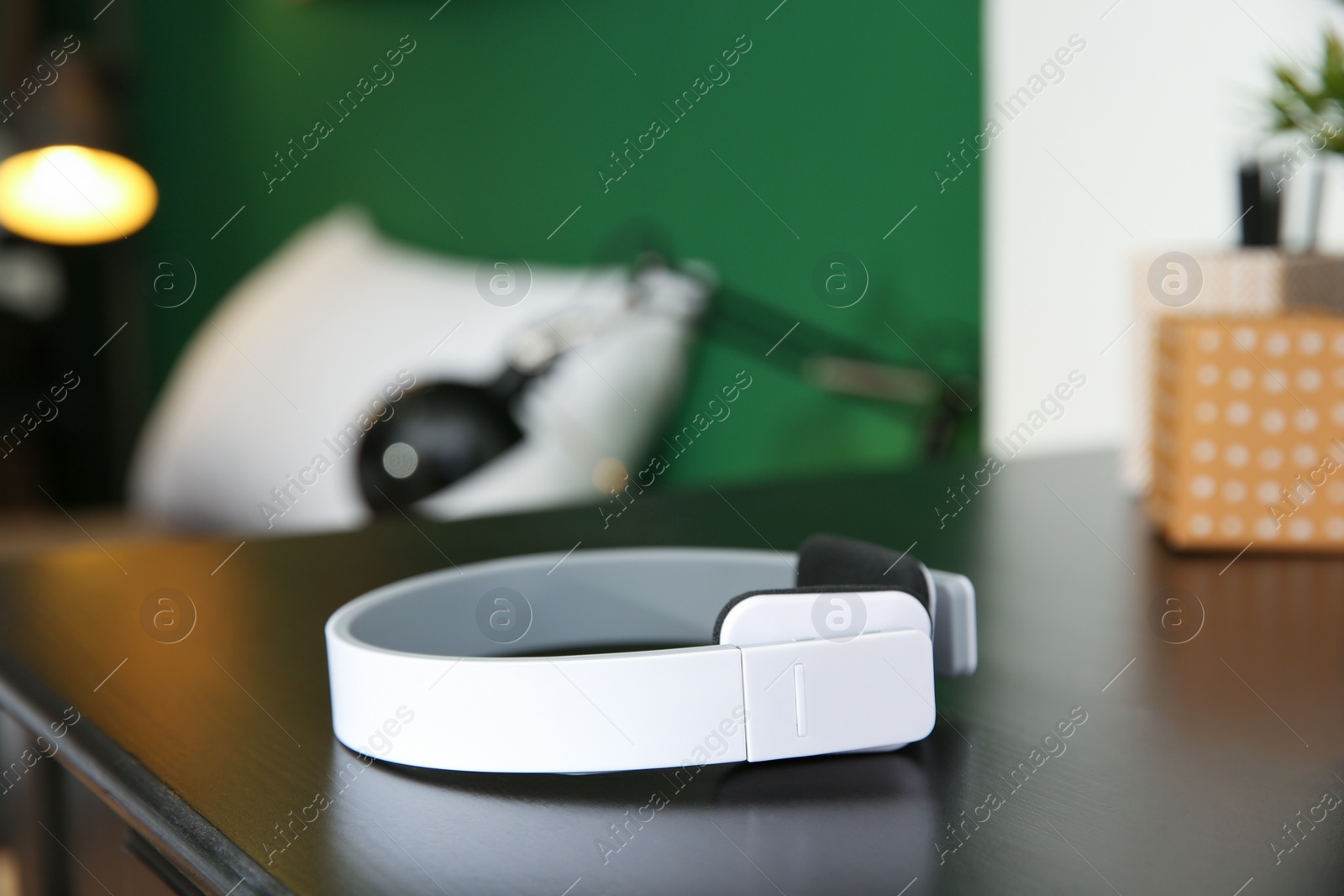 Photo of Stylish modern wireless headphones on table against blurred background, space for text