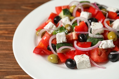 Photo of Plate with delicious fresh salad on table, closeup