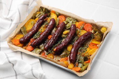 Photo of Baking tray with delicious smoked sausages and vegetables on white table, closeup