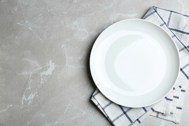 Photo of Empty white plate and napkin on light grey marble table, flat lay. Space for text